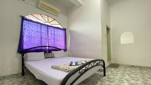 A single bed with a metal frame, a white mattress, and a purple canopy. - Hotel O California (Batam)