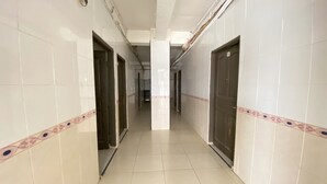 A corridor with white tiled walls and a patterned border, leading to a central pillar. - Hotel O California (Batam)
