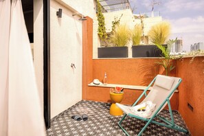 A small balcony with a patterned floor, a yellow toilet, a blue chair, and potted plants. - Savanna Dizengoff - Smart Hotel by Loginn Tel Aviv (Tel Aviv)