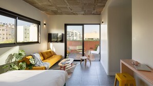 A modern hotel room with a large bed, a sofa, a small table, and a balcony with a view of the city. - Savanna Dizengoff - Smart Hotel by Loginn Tel Aviv (Tel Aviv)