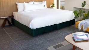A modern hotel room with a large bed, a small bedside table, a round coffee table, and a view of the outdoors through a window. - Savanna Dizengoff - Smart Hotel by Loginn Tel Aviv (Tel Aviv)