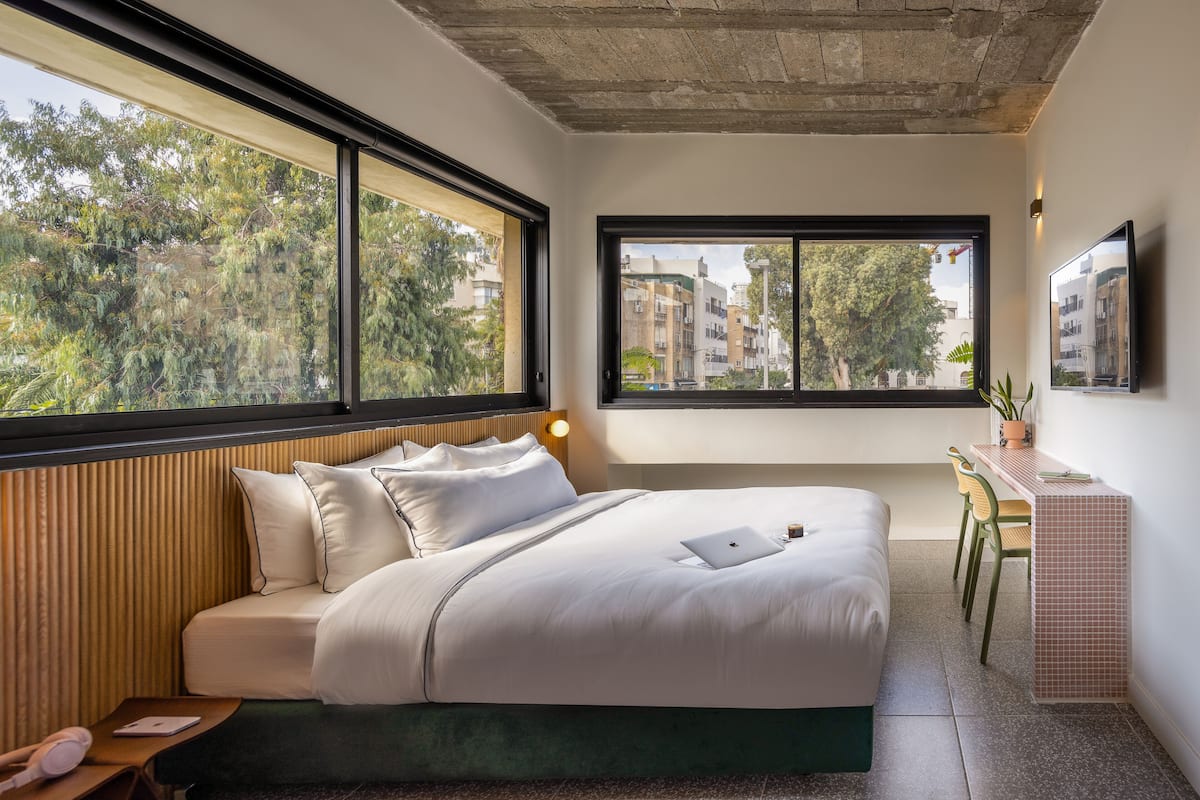 Ein modernes Hotelzimmer mit einem großen Bett, einem Schreibtisch und Blick auf die Stadt.