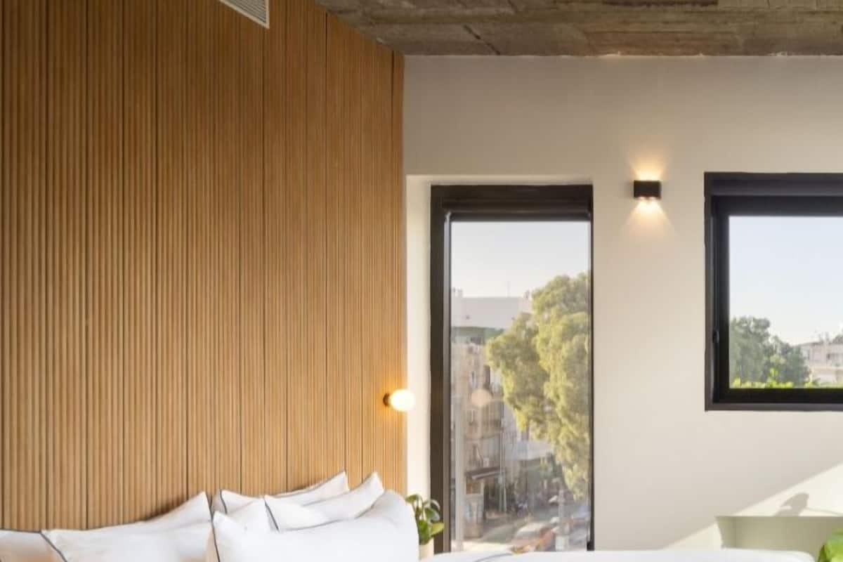 Ein modernes Schlafzimmer mit einem großen Bett, einer Wand aus Holzpaneelen und Blick durch eine Glastür.