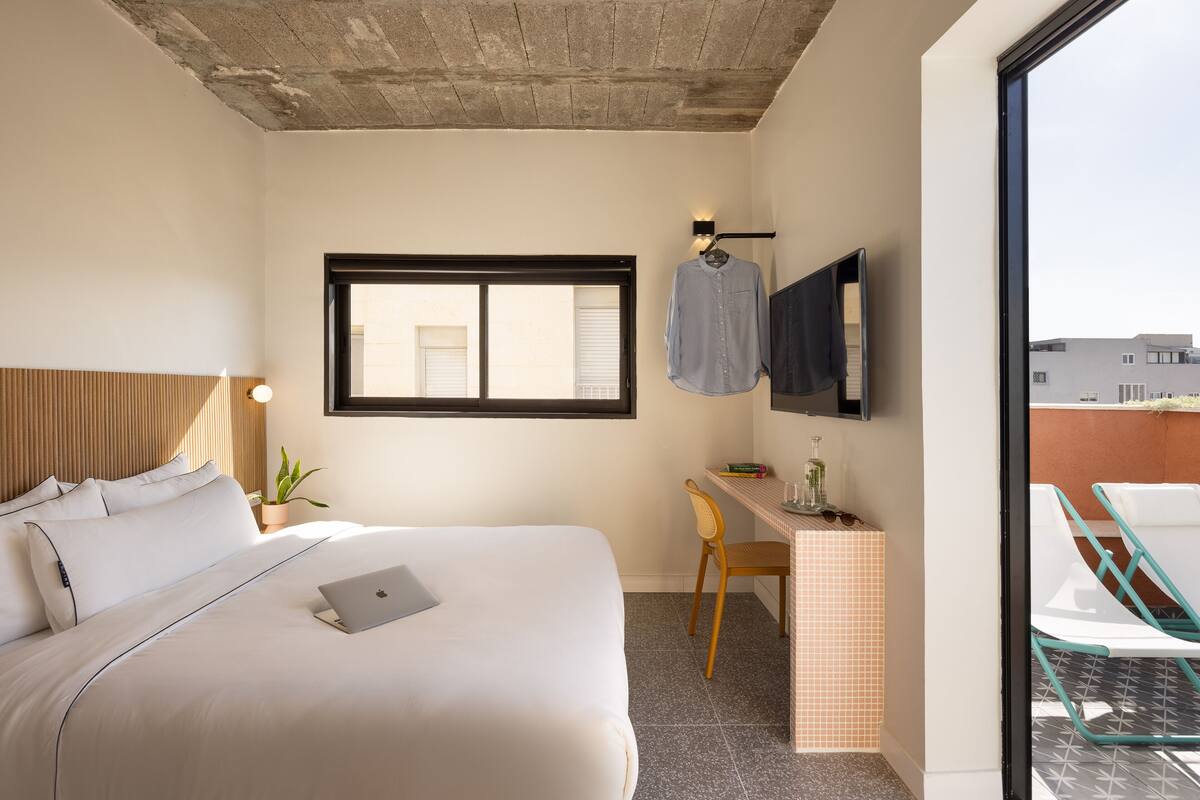 Ein Hotelzimmer mit Bett, Schreibtisch, Stuhl und einem großen Fenster.