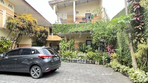 A car parked in a paved courtyard with a building in the background. - OYO Life 93398 Sudimoro Guest House Syariah (Malang)