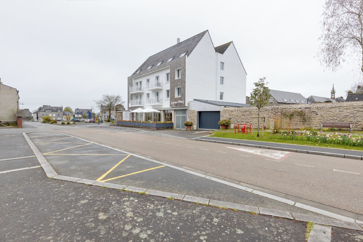 A hotel with a modern design, a parking lot, and a stone wall.