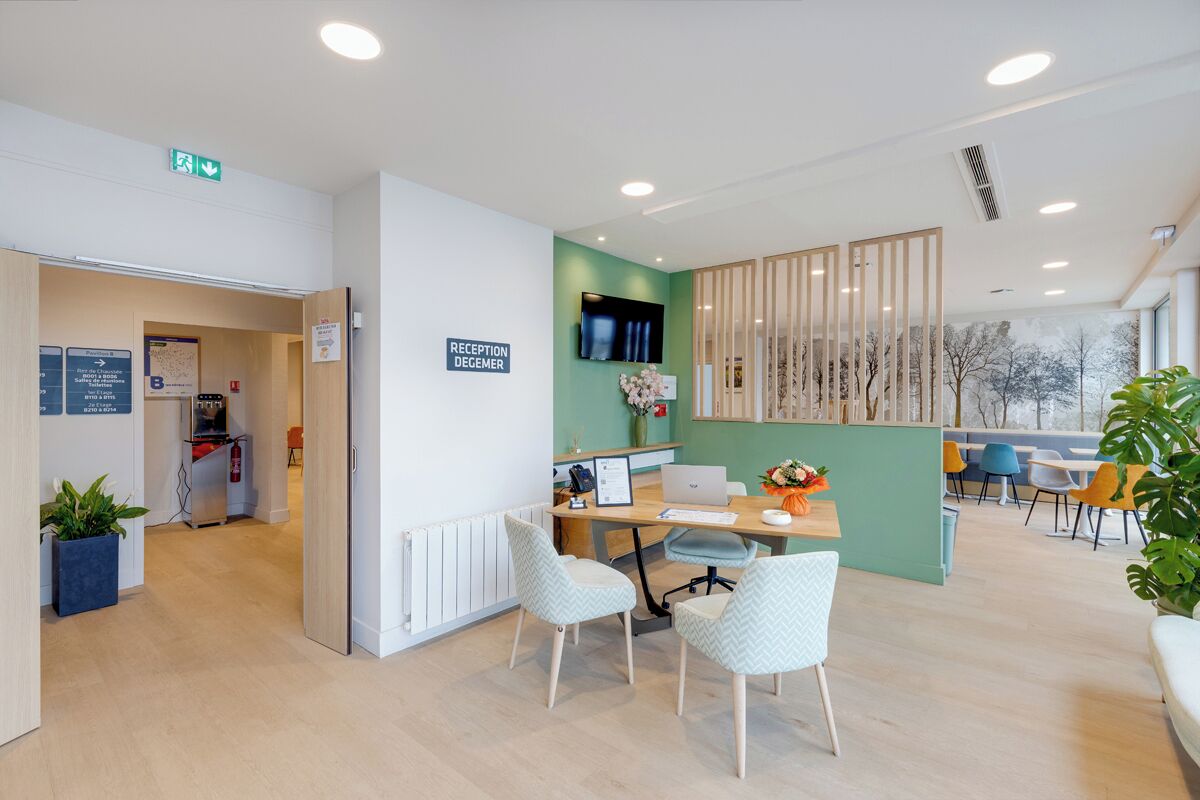 A reception area with a desk, chairs, a TV, and a sign indicating a reception desk.