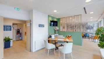 A reception area with a desk, chairs, a TV, and a sign indicating a reception desk.