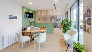 A reception area with a desk, chairs, a TV, and a sign that reads 'RECEPTION DEGEMER.' - Brit Hotel Confort Carhaix (Carhaix-Plouguer)