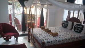 Ein Schlafzimmer mit Baldachinbett, einem roten Sessel und Blick ins Freie.