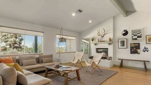 A spacious living room with a large window, a fireplace, and a cozy seating area.