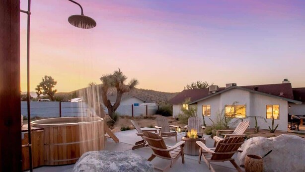 An outdoor patio with wooden chairs, a fire pit, and a hot tub.
