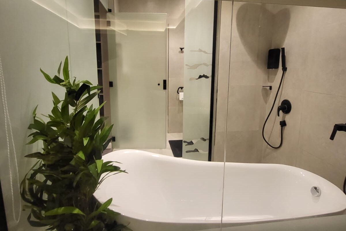Un baño moderno con una bañera acristalada, una planta en maceta y una zona de ducha.