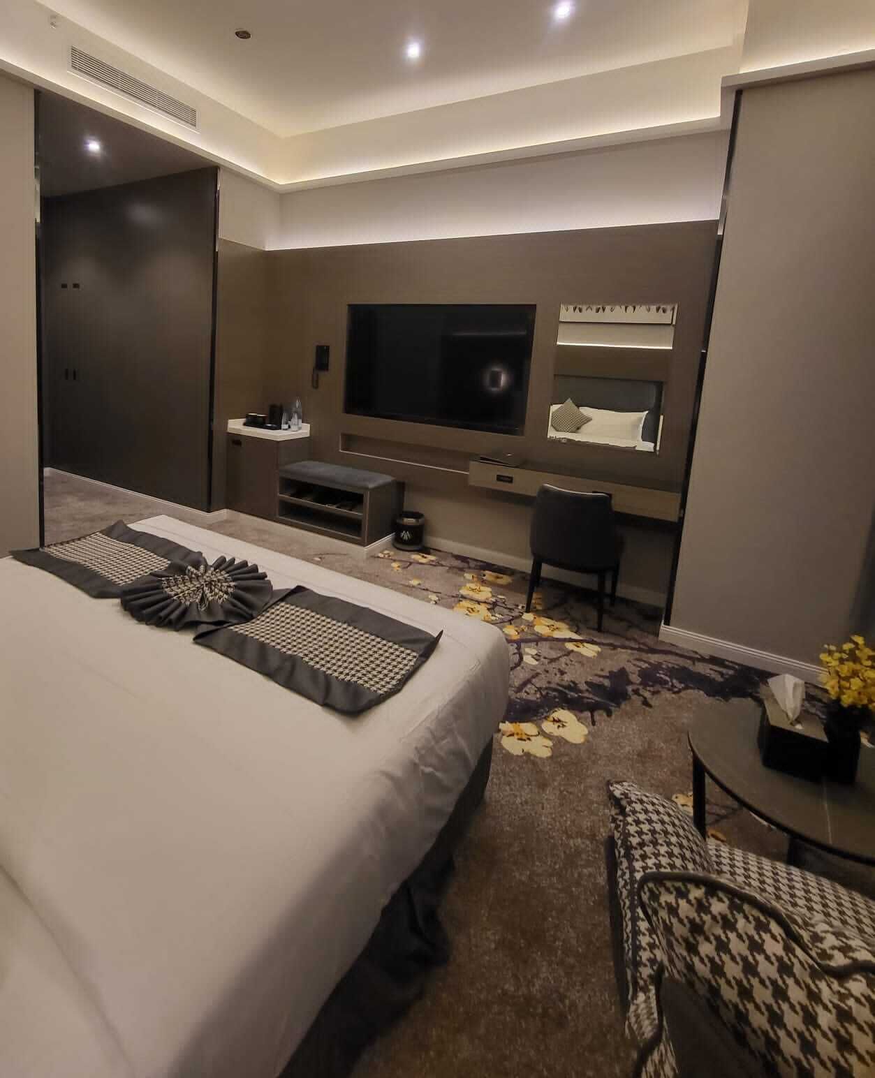 Une chambre d’hôtel moderne dotée d’un grand lit, d’une télévision à écran plat, d’un bureau et d’un coin salon.