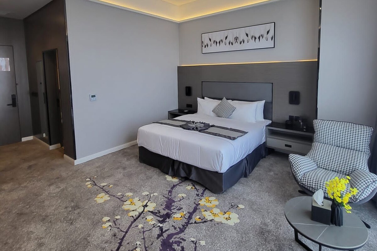 A modern bedroom with a bed, a chair, and a decorative rug.