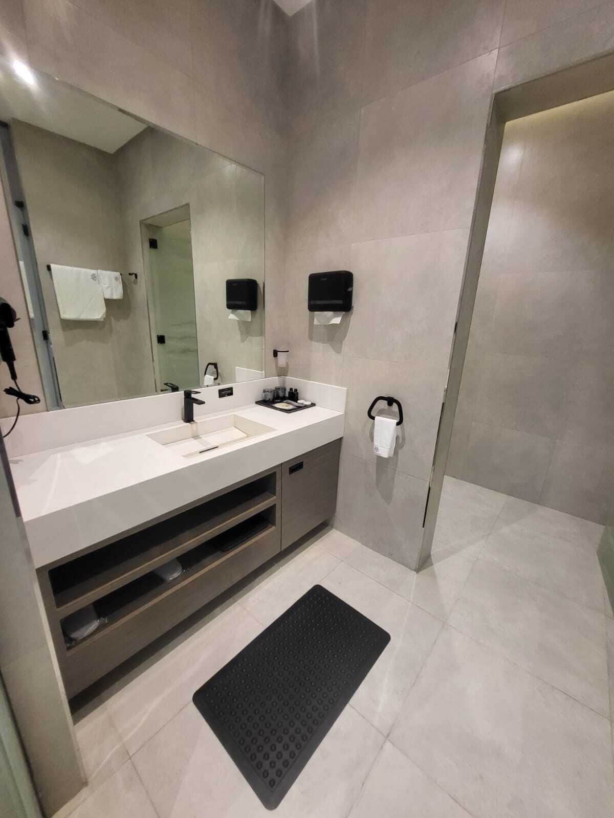 A modern bathroom with a large mirror, a sink, a vanity, and a towel rack.
