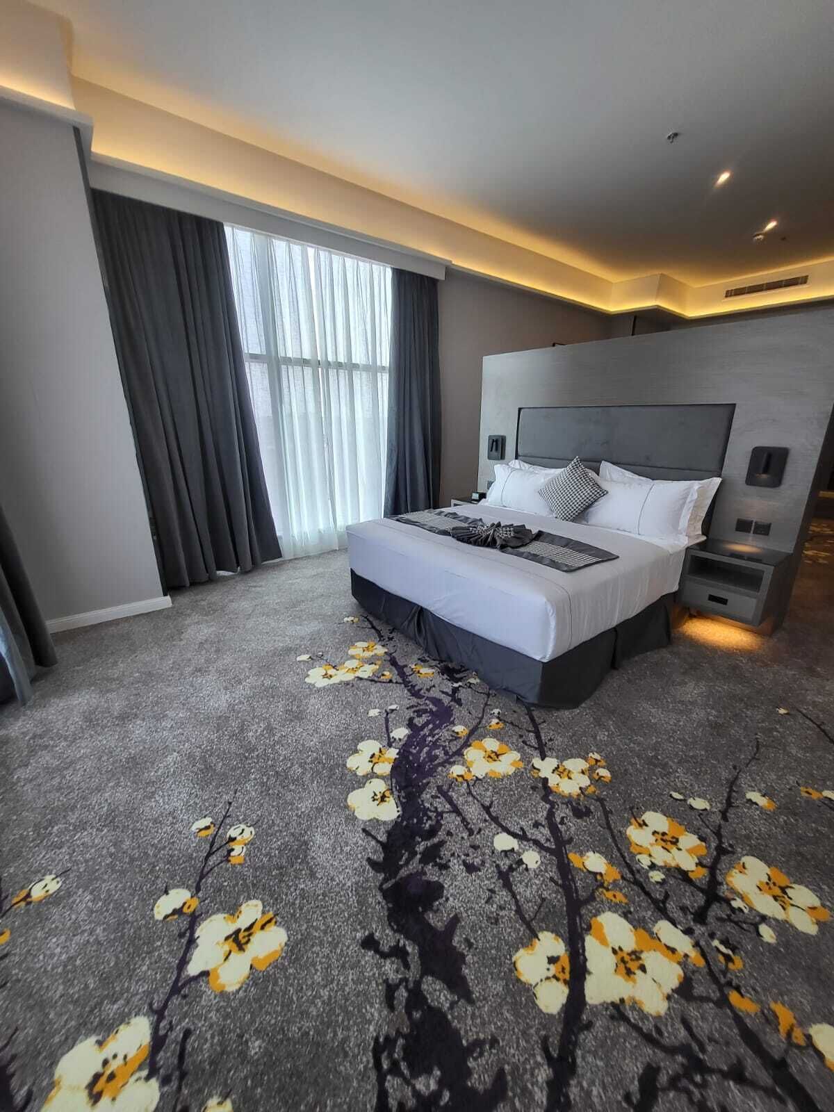 Une chambre d’hôtel moderne dotée d’un grand lit, d’une table de chevet, d’un téléviseur intégré et d’une fenêtre avec des rideaux.