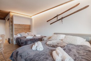 A modern hotel room with two beds, wooden headboards, and a ski rack on the wall. - Charmant Studio Avec une vue Imprenable (Nendaz)