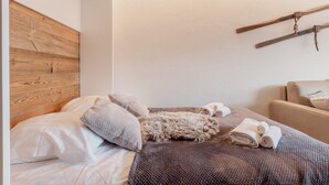A bedroom with a wooden headboard, a bed with white bedding, a fur throw, and a wooden beam on the wall. - Charmant Studio Avec une vue Imprenable (Nendaz)