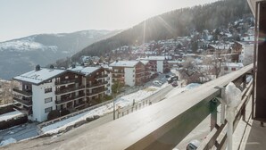 Ein Wohngebiet mit mehrstöckigen Gebäuden, einer verschneiten Straße und einer Bergkulisse im Hintergrund.