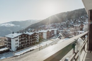 A residential area with multi-story buildings, a snow-covered road, and a mountainous backdrop. - Charmant Studio Avec une vue Imprenable (Nendaz)