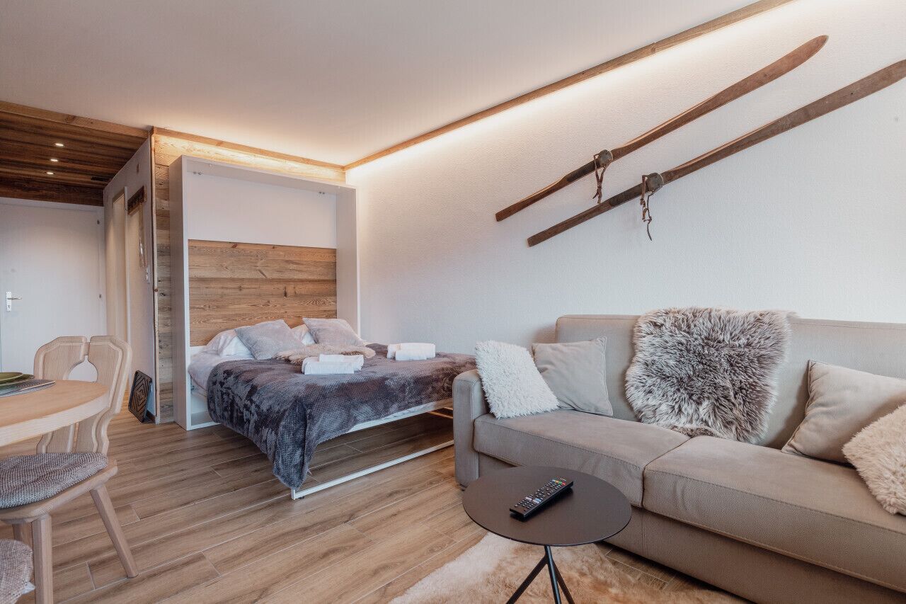 Une chambre moderne avec un lit, un canapé, une petite table et un porte-skis fixé au mur.