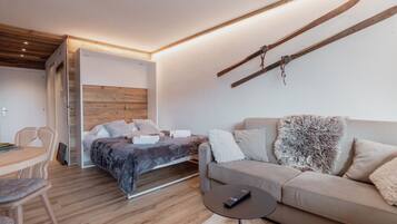 Une chambre moderne avec un lit, un canapé, une petite table et un porte-skis fixé au mur.
