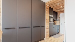 Eine moderne Küche mit dunklen Schränken, Holzboden und einem eingebauten Backofen.
