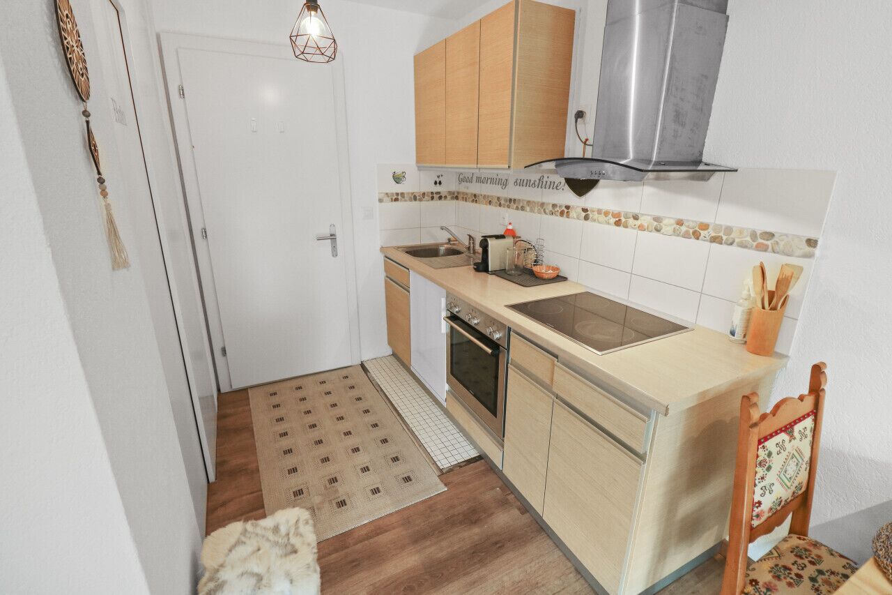 Et kompakt køkken med træskabe, et rustfrit stål emfang, en indbygget ovn og en lille bordplade.
