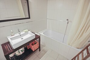 Un baño con lavamanos, espejo y bañera blancos.