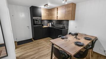 A modern kitchen with wooden cabinets, a built-in oven, and a dining area with a wooden table and chairs.