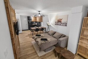 A compact living space with a sofa, a dining table, and a kitchen area. - Appartement rénové avec vue panoramique et sauna (Saas-Fee)