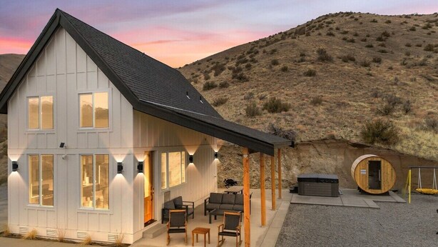 Une maison moderne dotée d’un patio couvert, d’un sauna et offrant une vue sur un paysage vallonné.
