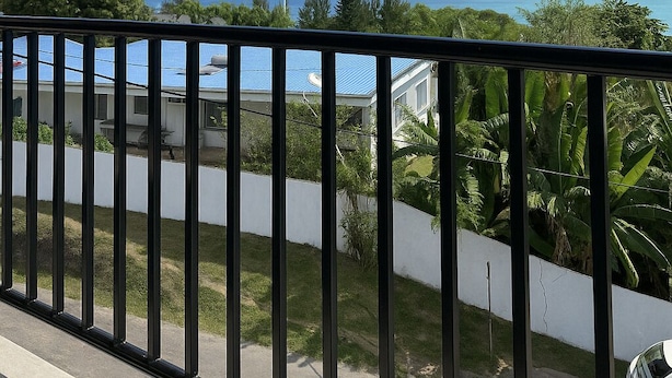 Un balcon avec vue sur un navire de croisière, de la verdure et un ciel dégagé.