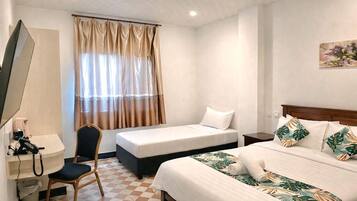 A hotel room with a checkered floor, a desk with a telephone, a chair, two beds with different bedding, and a window with curtains.