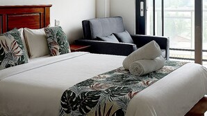 Une chambre à coucher avec un grand lit, une chaise, une table de chevet et une fenêtre donnant sur un beau paysage.