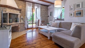 Un salon chaleureux avec une cheminée en pierre, un plancher en bois, un canapé blanc et un coin repas.