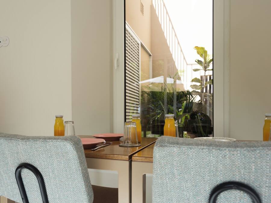 A dining area with two chairs, a table, and a window with a view of a building and plants.