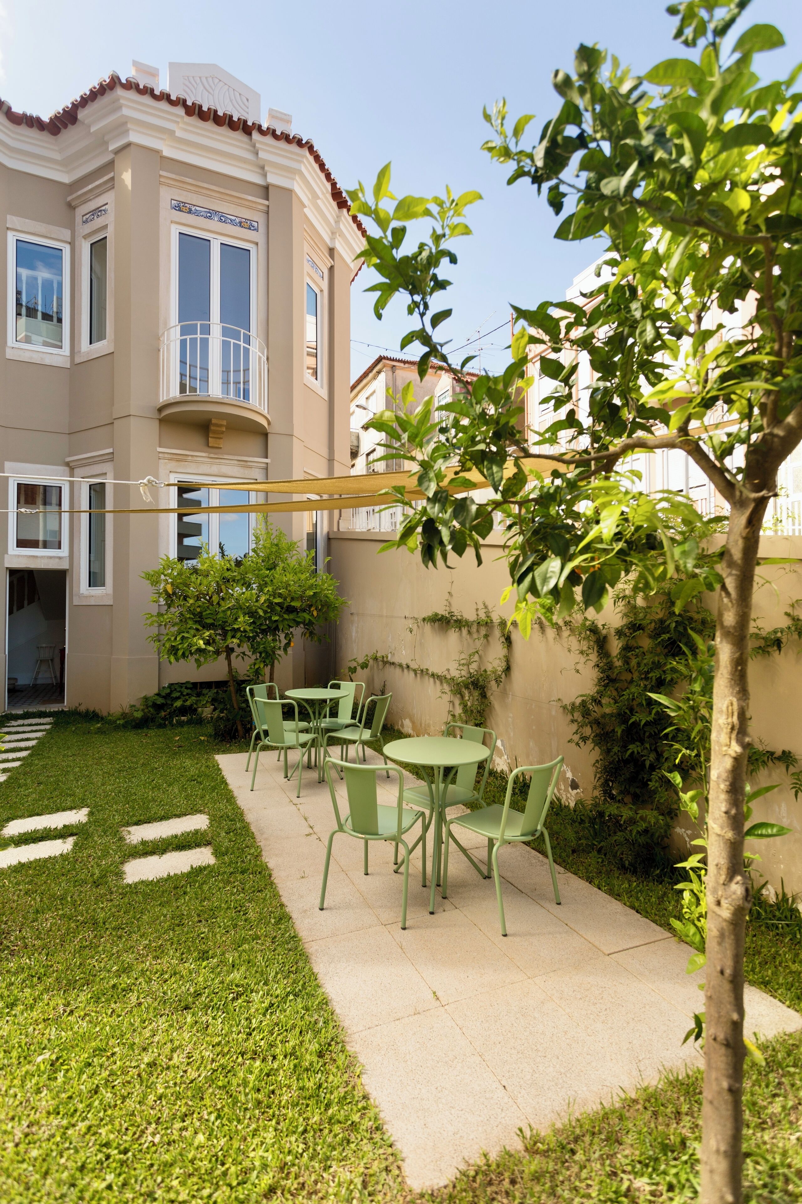 A courtyard with a green lawn, a small tree, and a table with chairs.