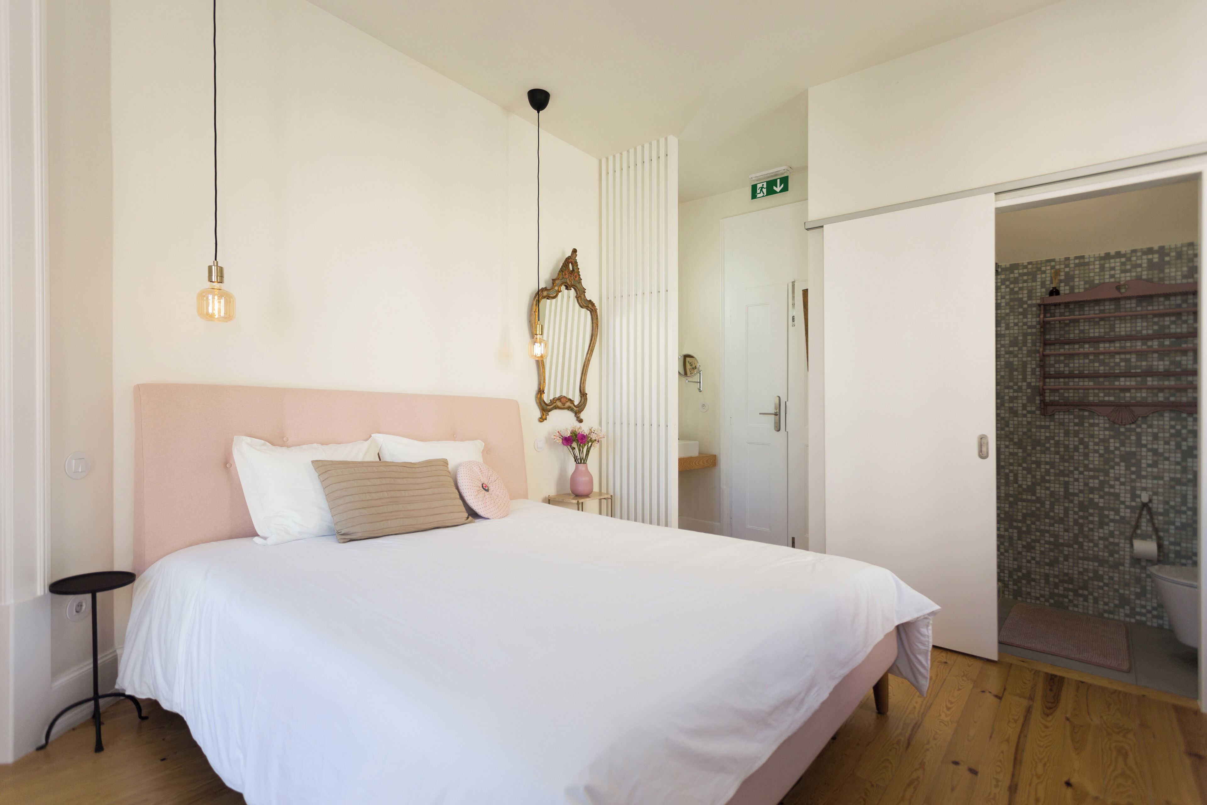 Un dormitorio con una cama grande, una mesita de noche, un espejo y una puerta que da a un baño.