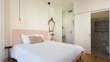 Un dormitorio con una cama grande, una mesita de noche, un espejo y una puerta que da a un baño.
