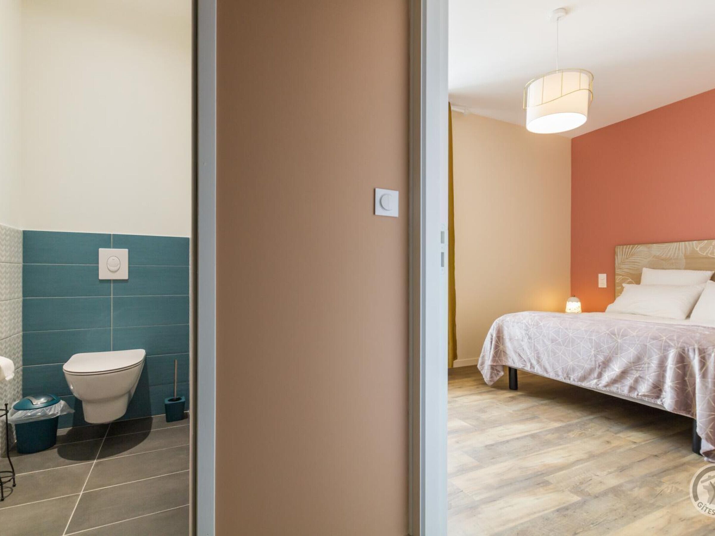 Una camera da letto con un letto, un comodino e una lampada a sospensione.