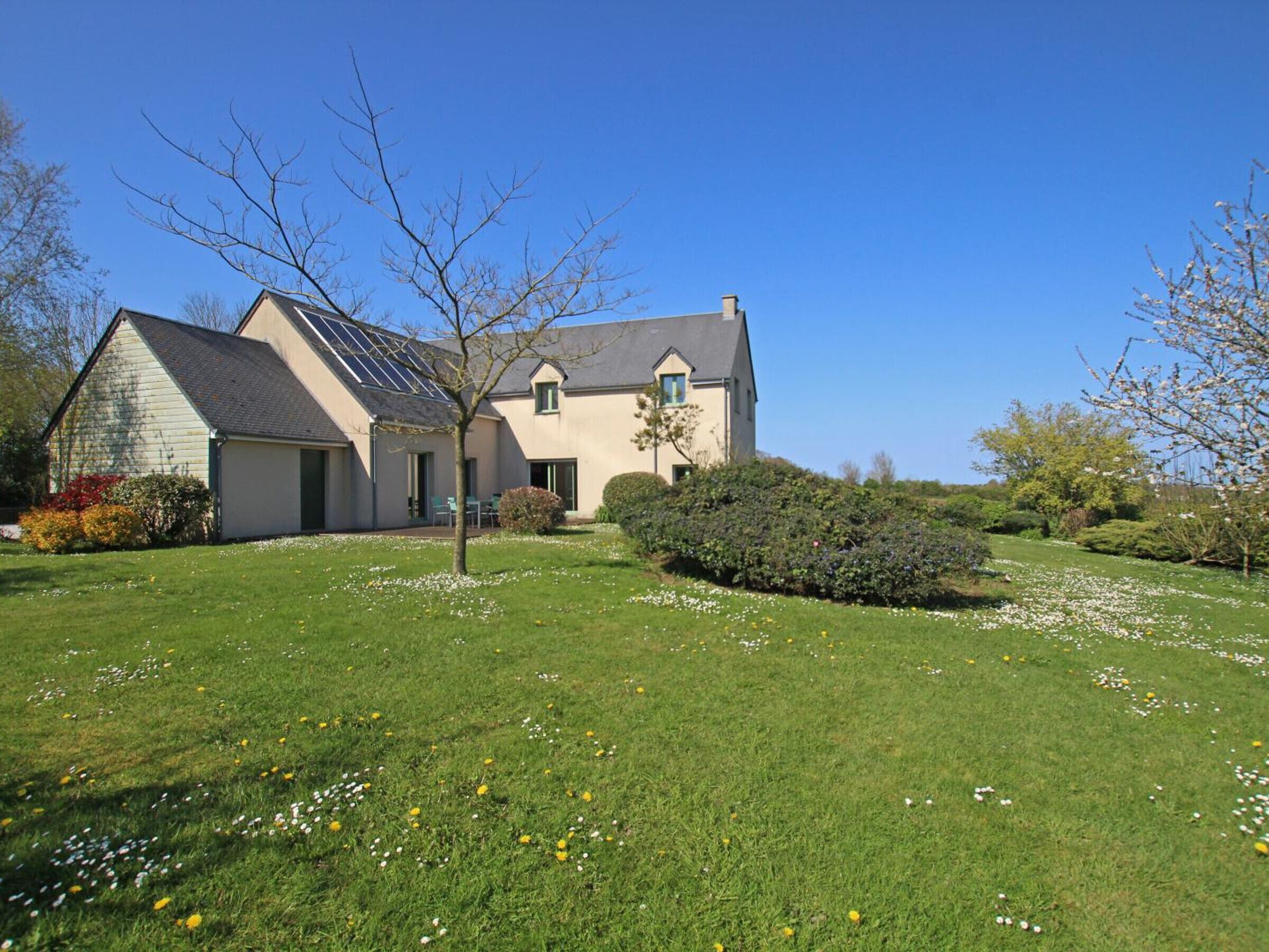 A two-story house with a sloped roof, a garage, and a small garden with flowers and shrubs.