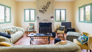A living room with a fireplace, two armchairs, a sofa, a coffee table, and a television. - Spacious house with garden near Utah Beach (Sainte-Marie-du-Mont)