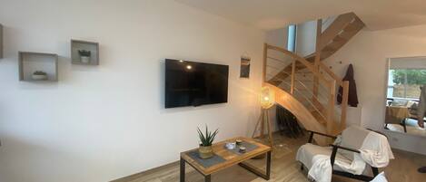 Una sala de estar moderna con televisor de pantalla plana, una mesa de centro de madera y una escalera.