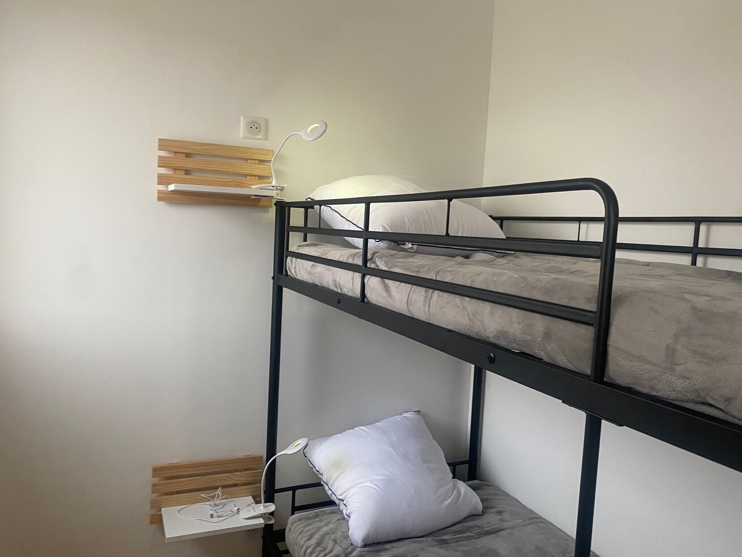 A bunk bed with a desk and chair, a white pillow, and a white lamp.