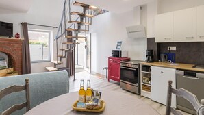 Une cuisine moderne dotée d’un îlot central, d’un coin repas avec une table ronde et d’un escalier menant à un niveau supérieur.