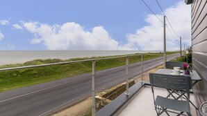 Un balcon avec vue sur la mer, une table avec des chaises et une rambarde.