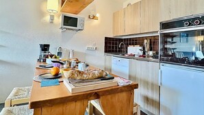 A compact kitchen with wooden cabinets, a built-in microwave, and a modern stove.