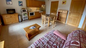 A compact living space with a kitchenette, a dining area, and a seating area with a sofa and a coffee table. - Beautiful 4-pers. apartment with balcony and garage in Grand-Bornand (Le Grand-Bornand)